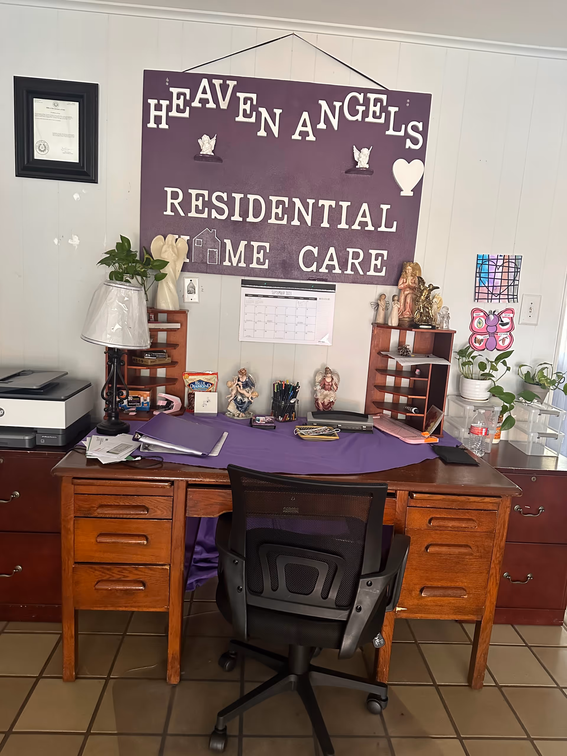 Office desk with purple cloth and a large Heaven Angels Residential Home Care sign