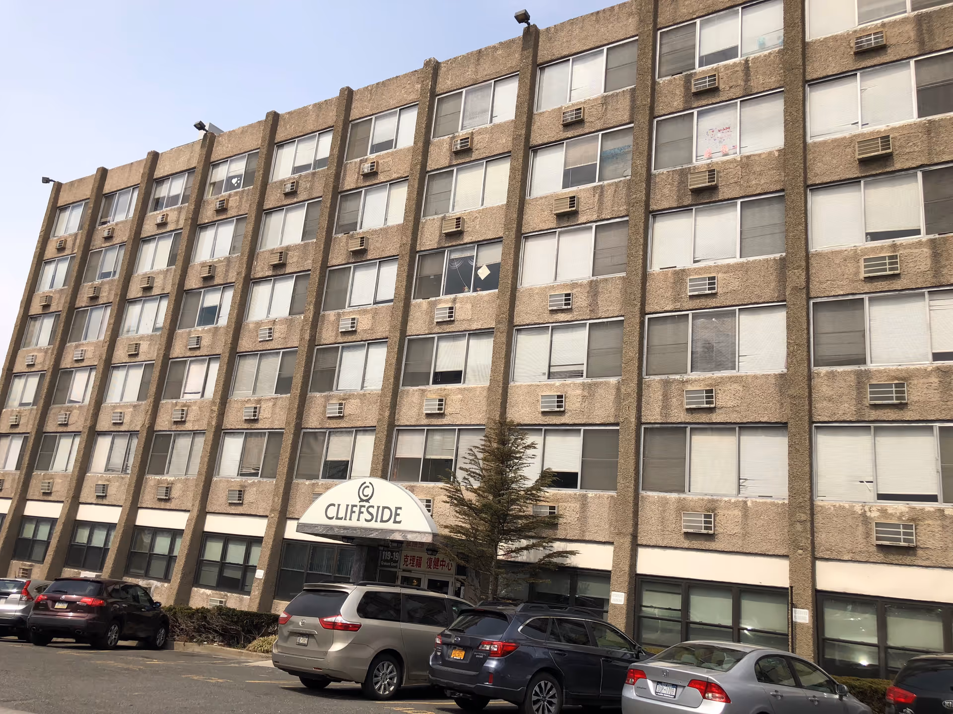 Tall beige building facade with Cliffside entrance sign and parked cars.