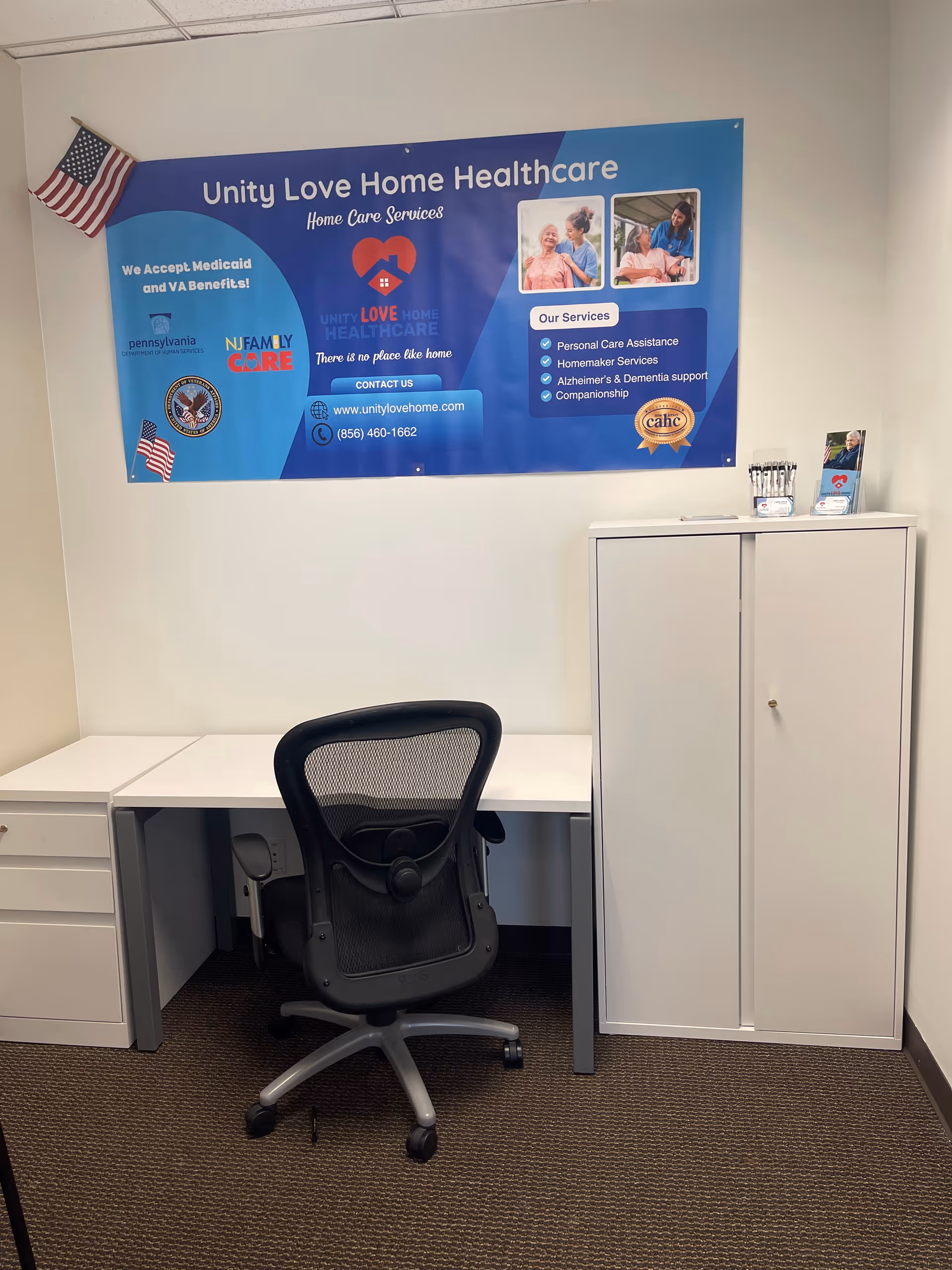 Interior office space with desk, chair, cabinet, and a Unity Love Home Healthcare banner.