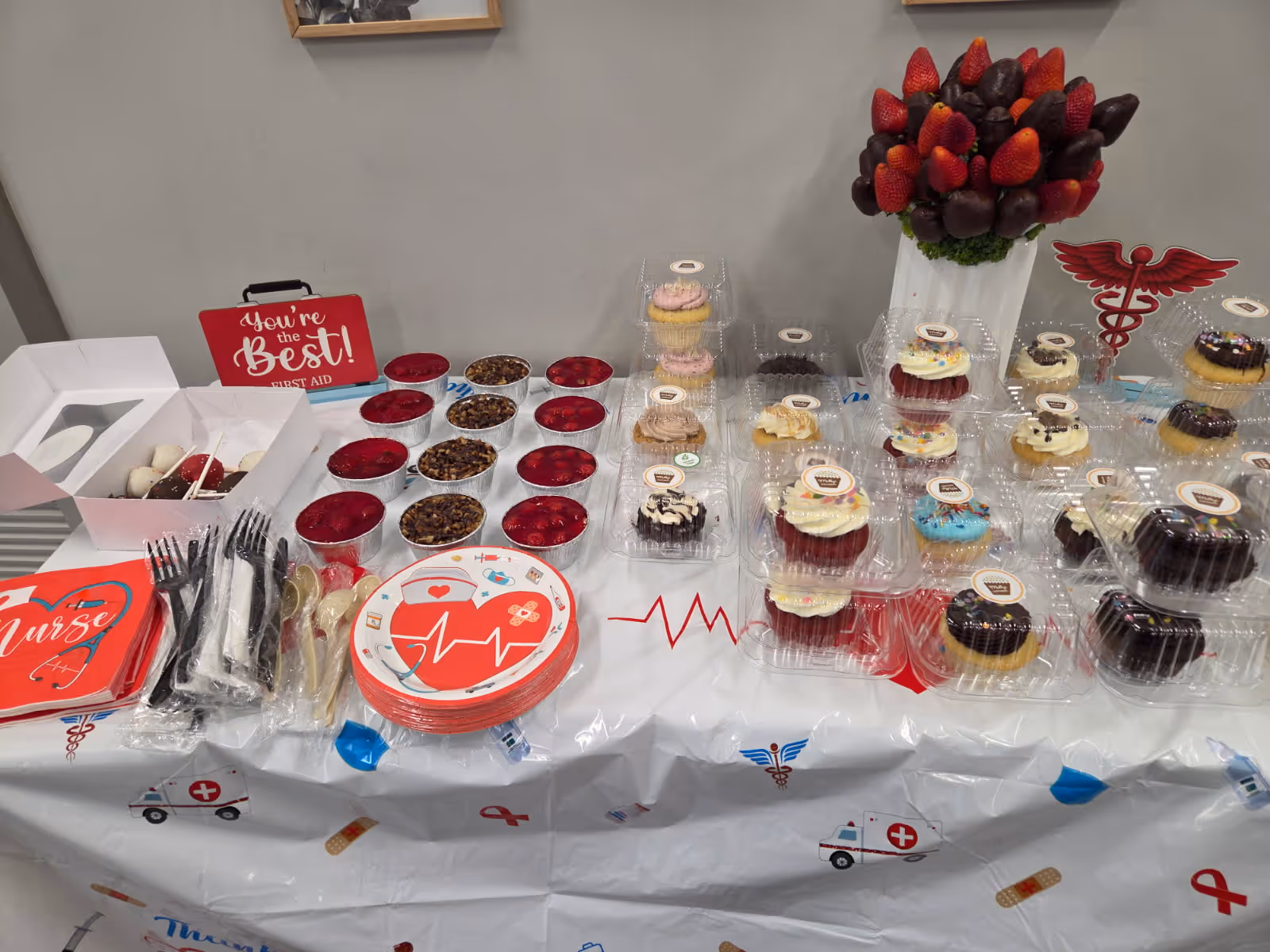 Dessert table with cupcakes, pastries, and medical-themed decor indoors.