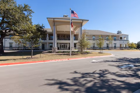 Exterior view of Truewood by Merrill Georgetown, a senior living facility with entrance canopy and flags.