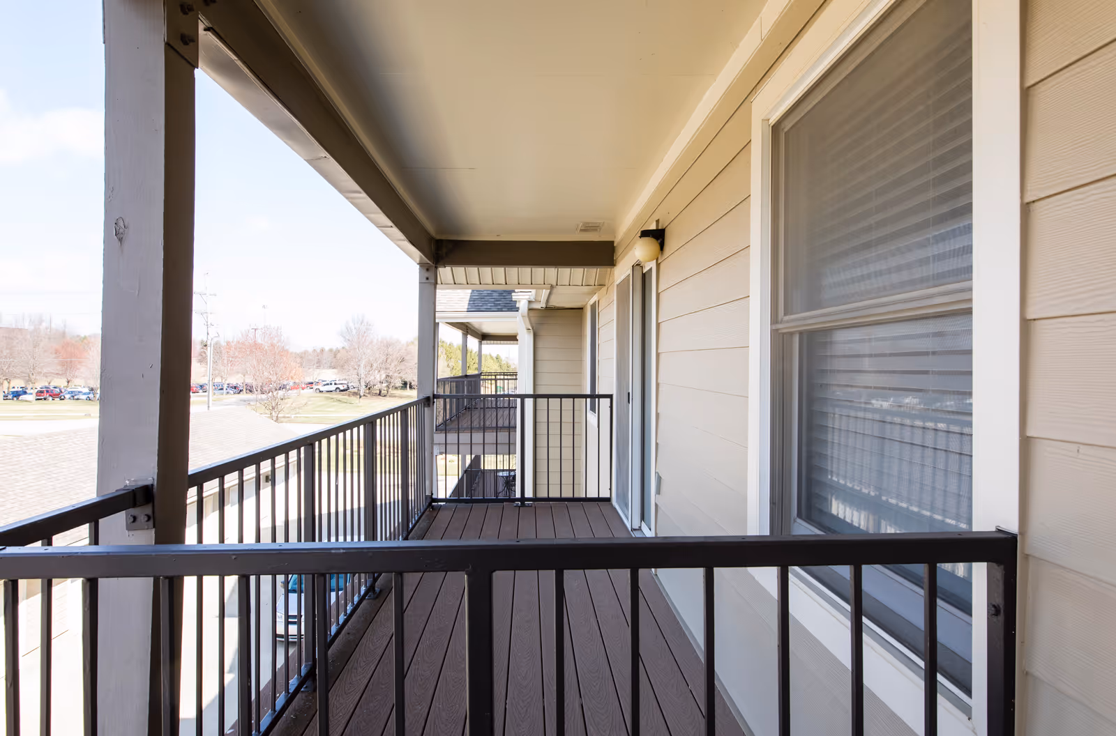 Covered second-floor balcony walkway with metal railings outside apartment units.