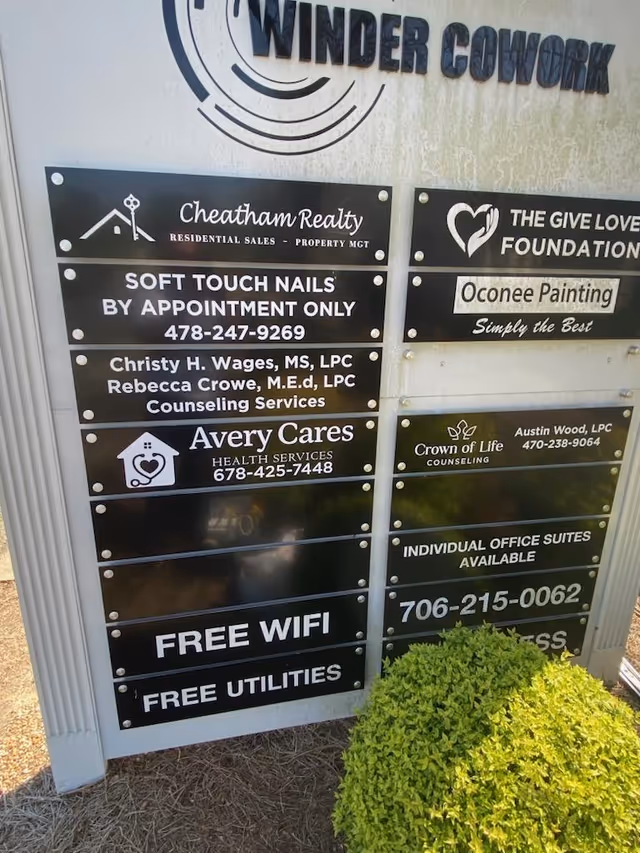 Exterior signboard displays multiple business plaques, including Avery Cares Health Services, with a shrub nearby.