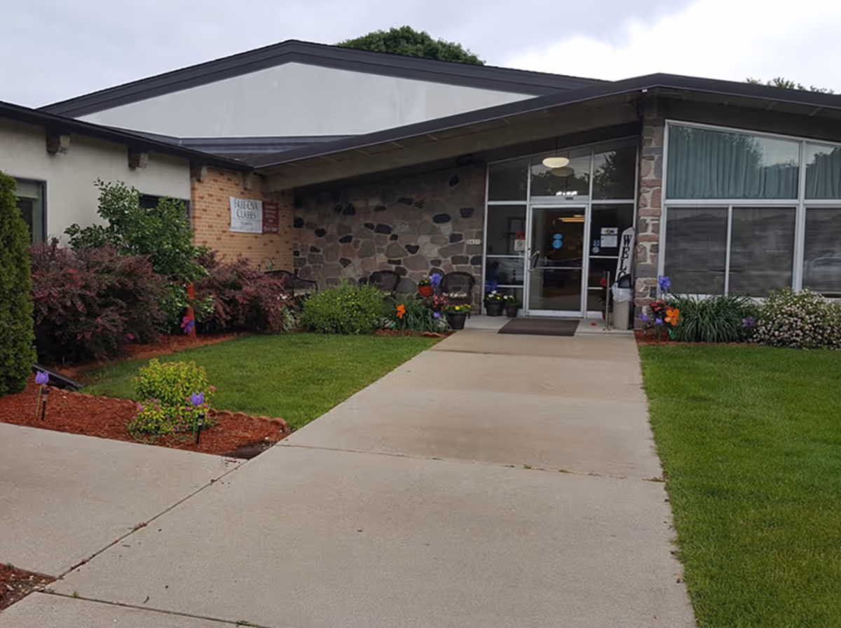 Front entrance of Mercy Health Services building with glass doors, stone walls, and well-kept landscaping.