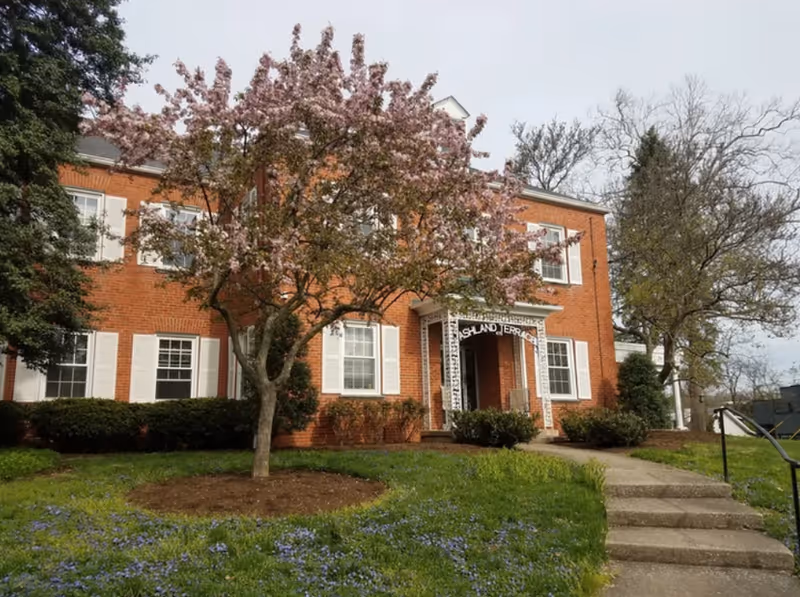 Ashland Terrace exterior: red brick building with white shutters and blooming trees.