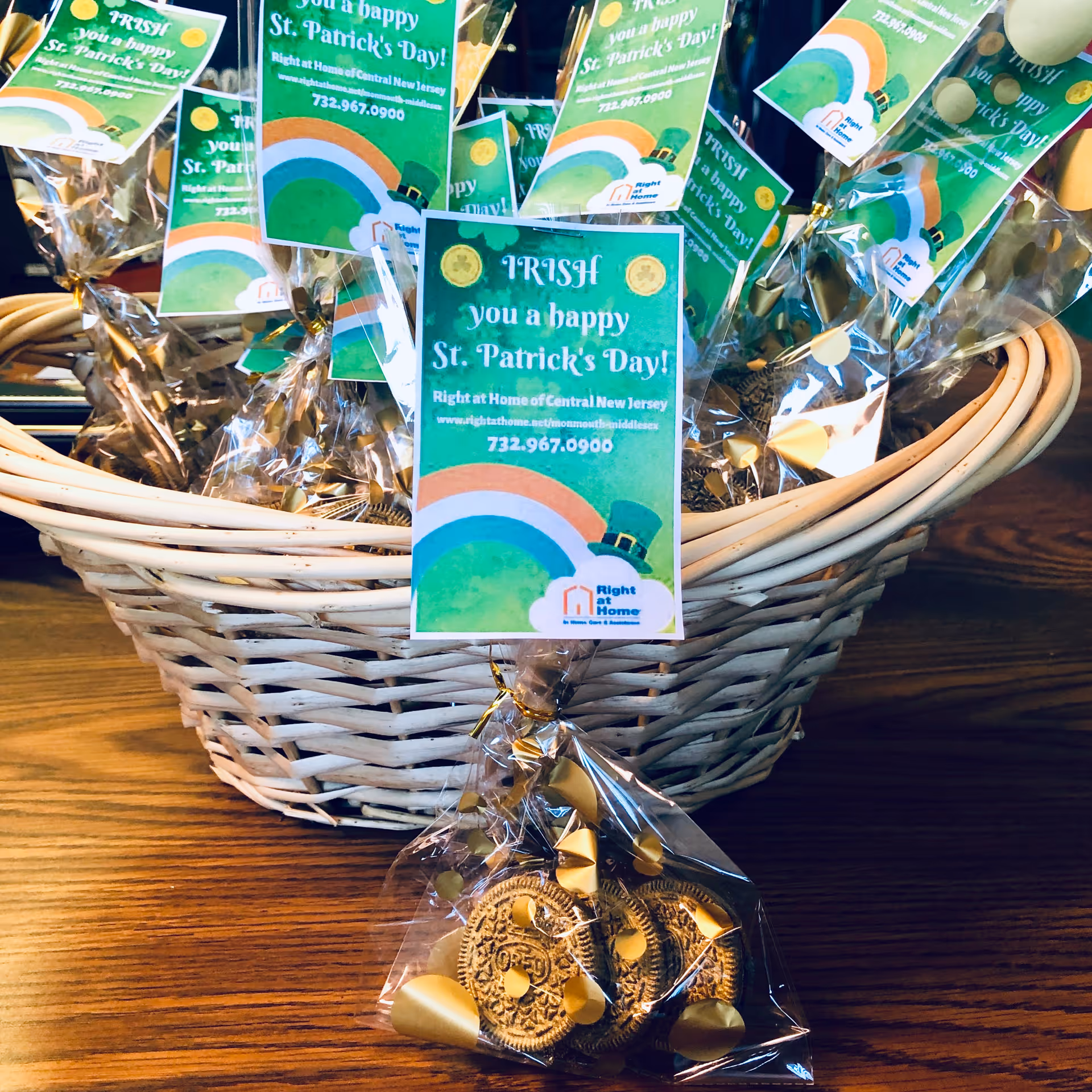Basket of St. Patrick's Day cards and a bag of chocolate coins on a wooden table.