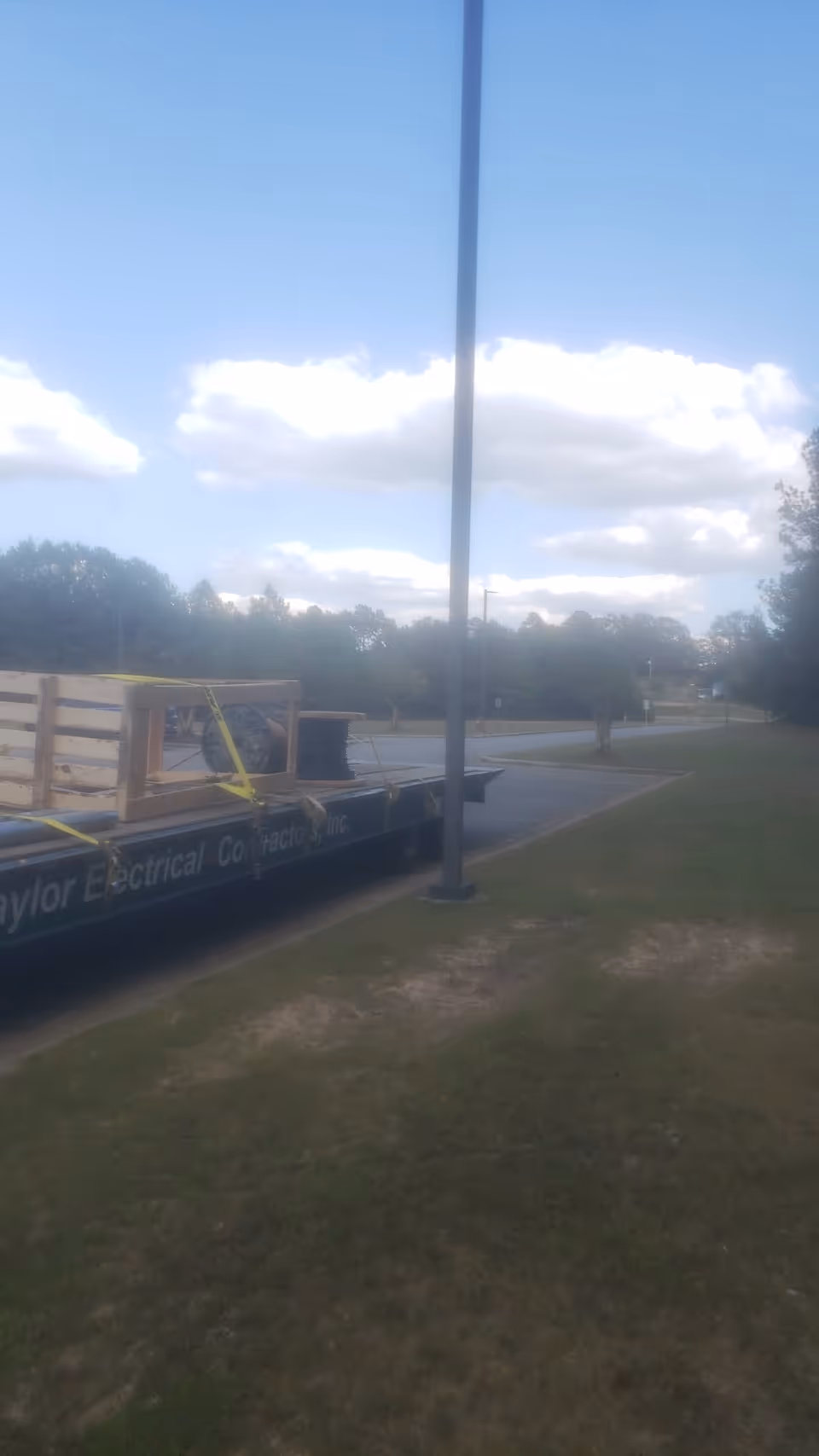 Outdoor street scene with a trailer, crate, and lamppost along a grassy area.