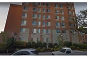 Exterior of Annie B Rose House, a brick, multi-story senior living building with parked cars.