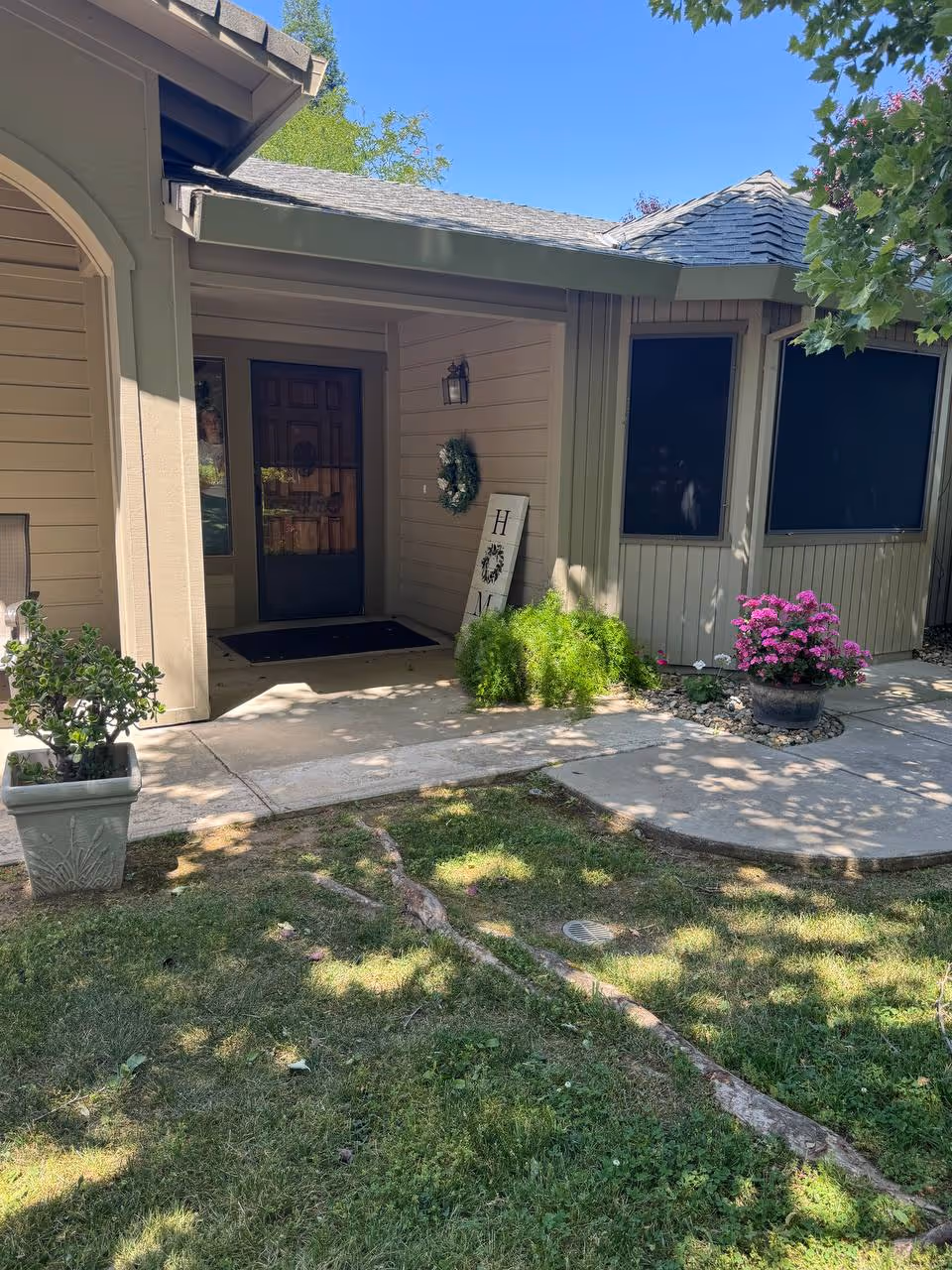 Front entrance of a senior living home with a wreath, sign, and potted plants.