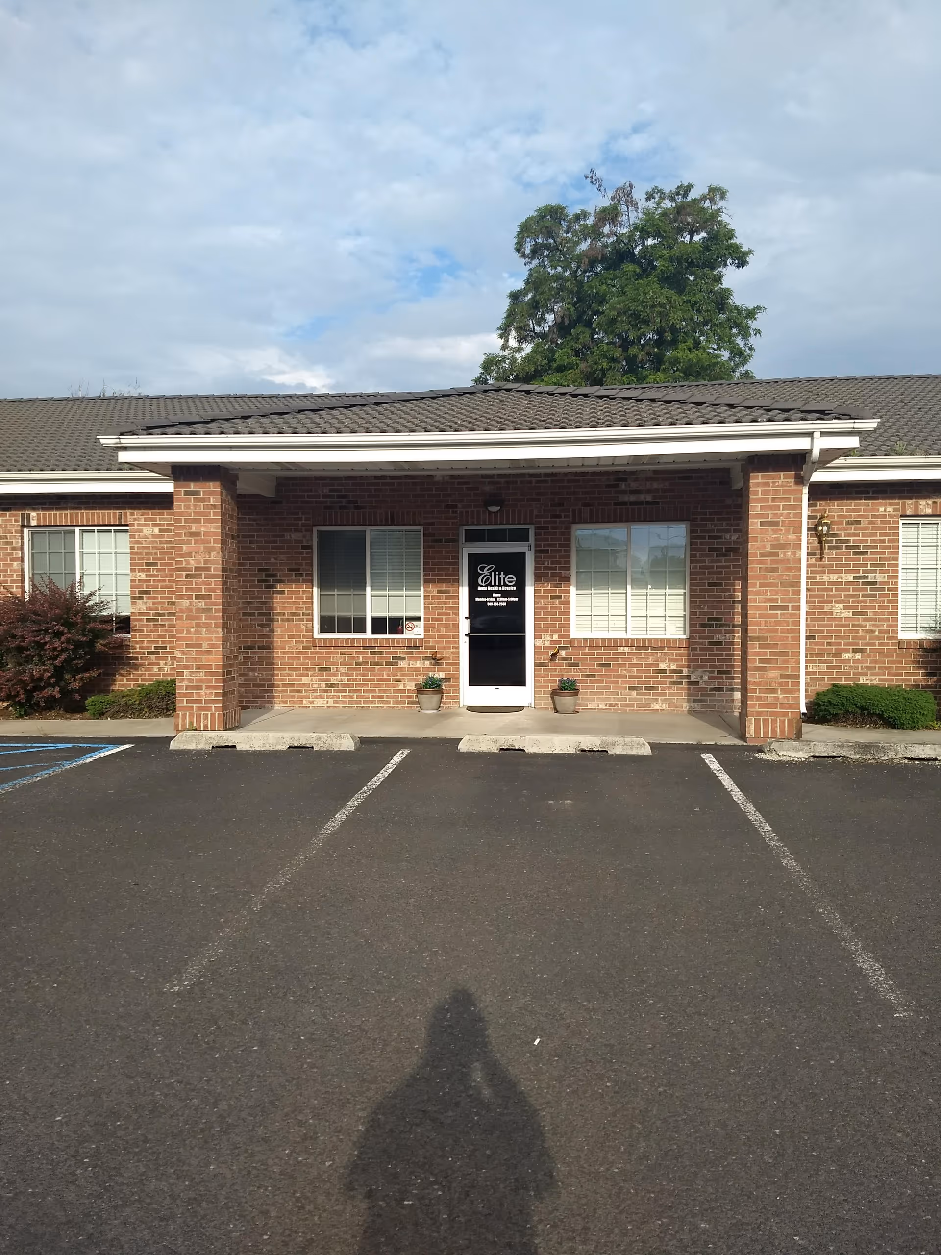 Brick single-story facility with a central glass door and surrounding parking area.
