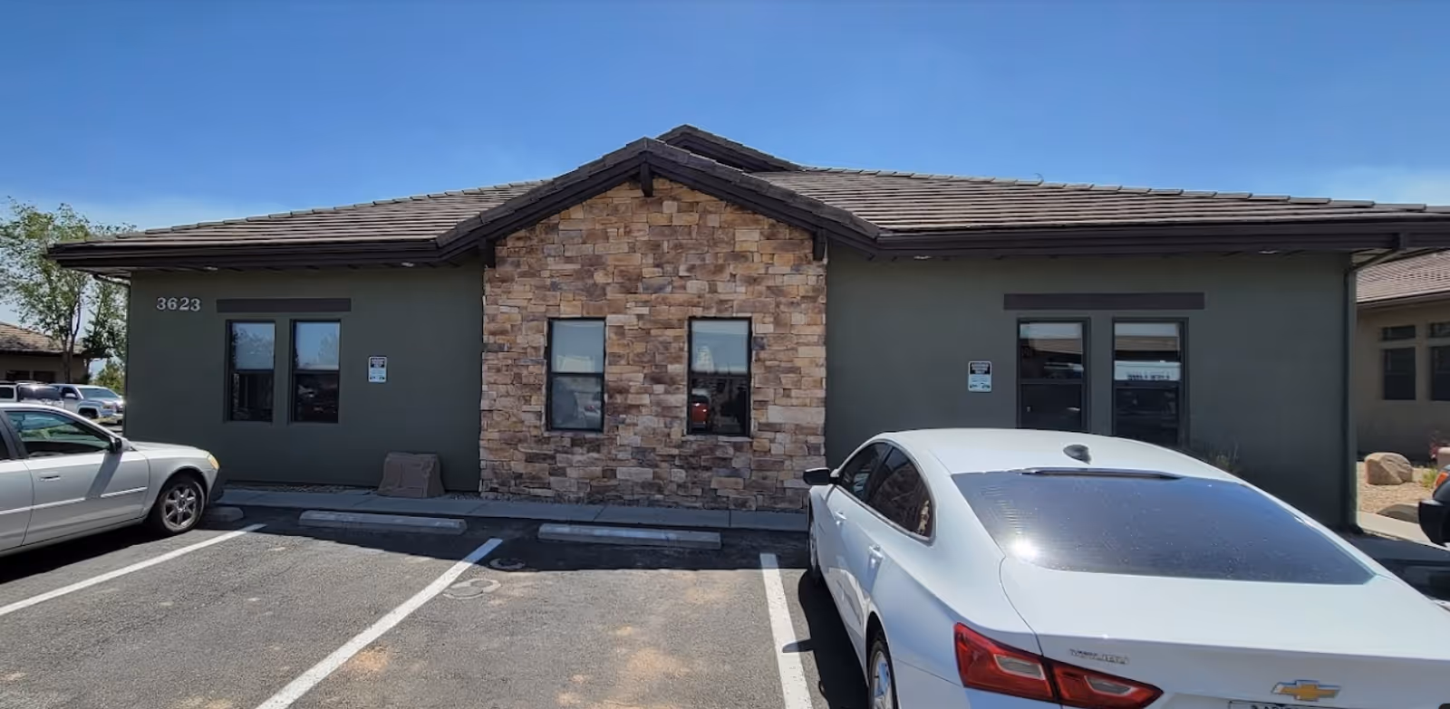 Front view of a single-story building with stone facade and cars in the parking lot