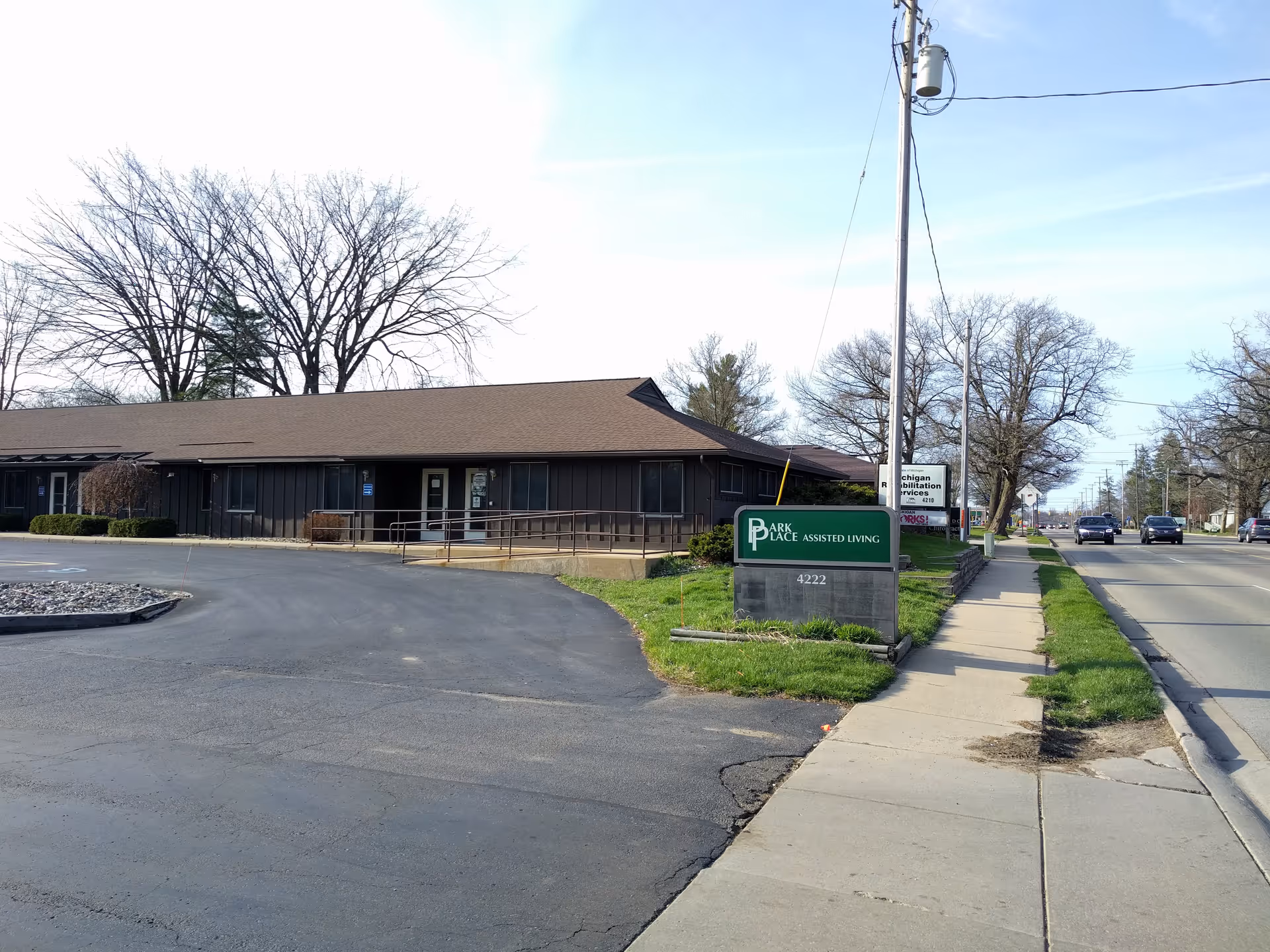 Exterior view of Park Place Assisted Living building with sidewalk and sign.