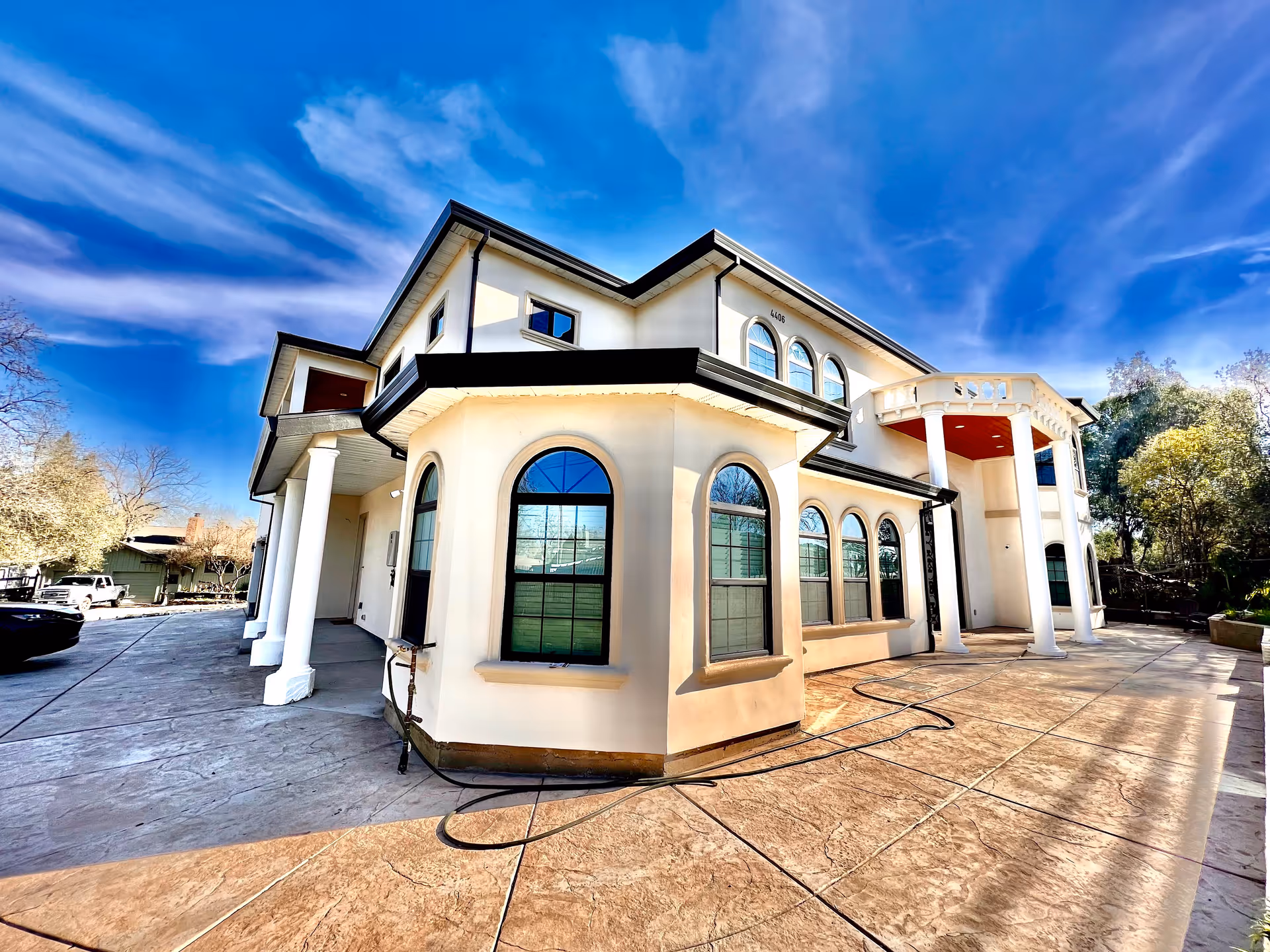 White senior care facility exterior with arched windows, columns, and a blue sky.