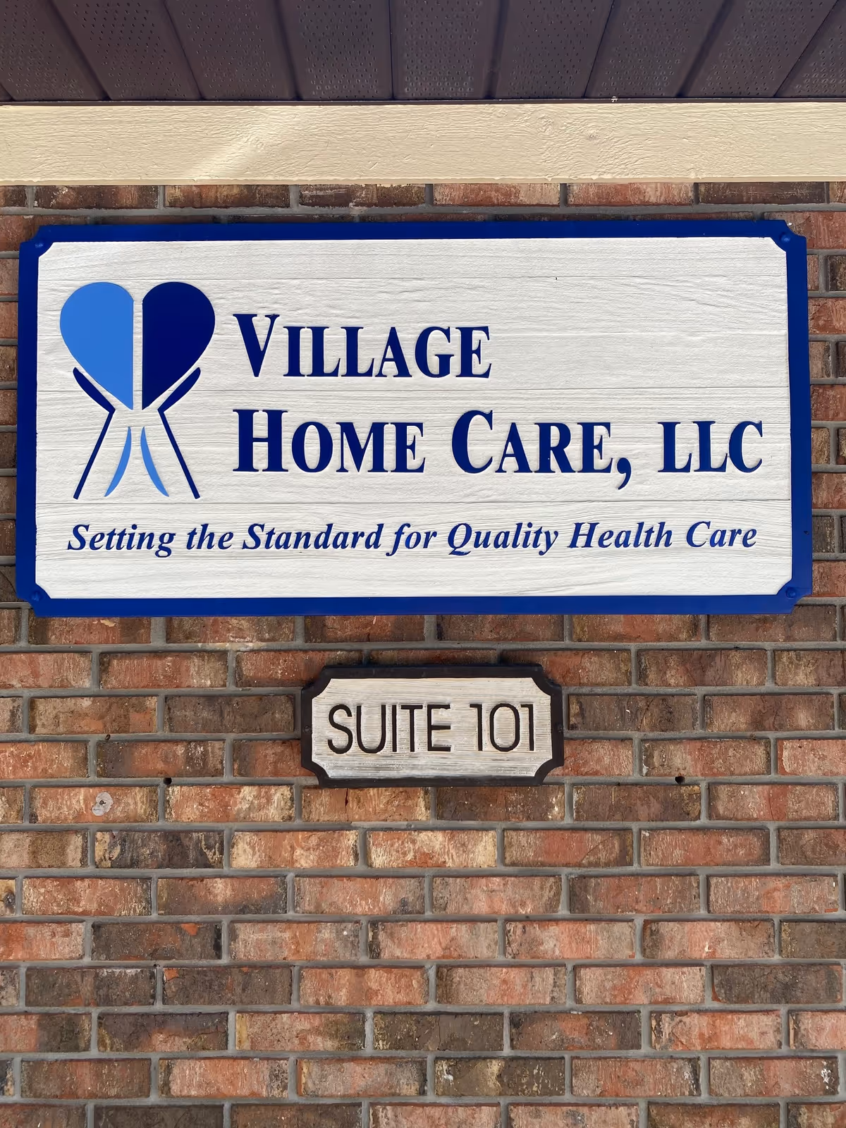 Sign for Village Home Care, LLC on a brick exterior wall, Suite 101.