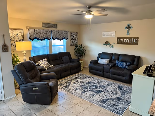 Cozy living room at Safe Haven Care Home of Seguin with dark leather sofas and decor.