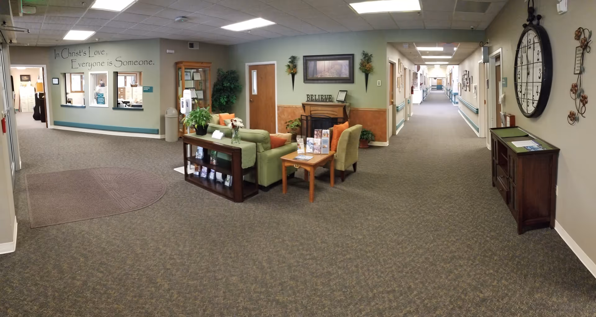 Interior lobby area with seating, a long corridor, and wall decorations in a senior living facility.