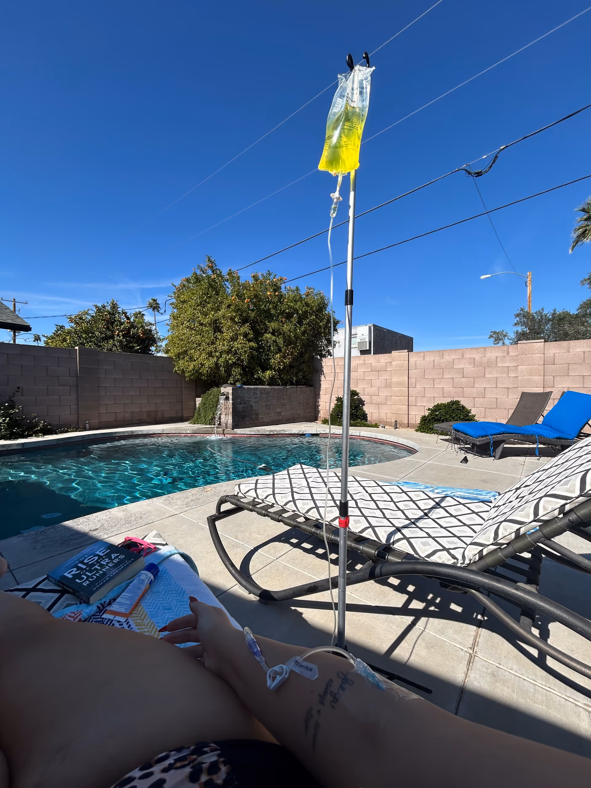Outdoor pool area with IV drip stand beside sun loungers.