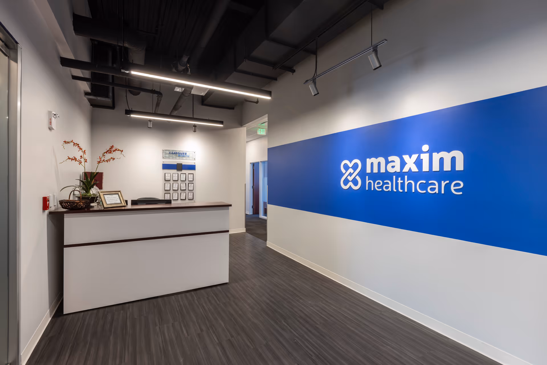 Reception desk in a hallway with a blue Maxim Healthcare sign on the wall.