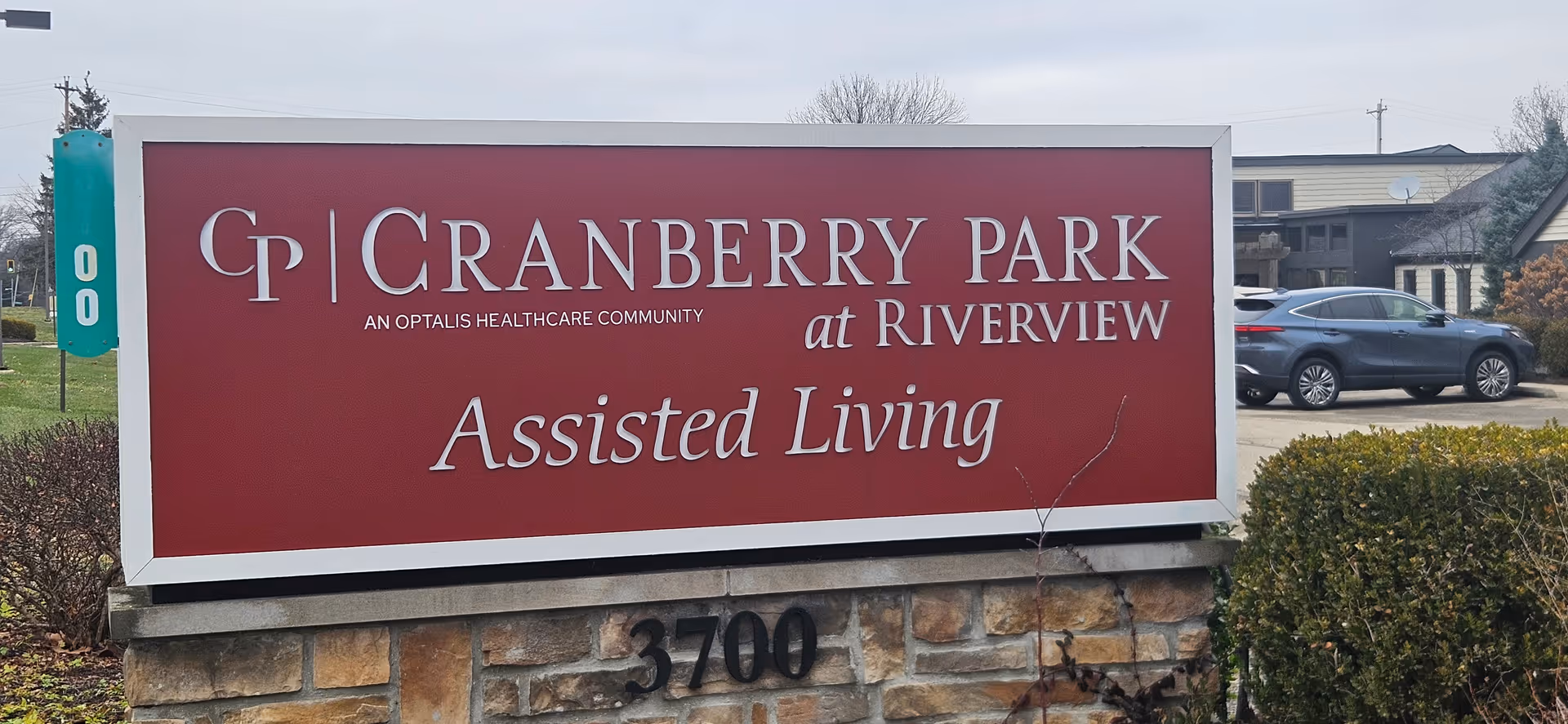 Large red sign with Cranberry Park at Riverview Assisted Living on a stone base