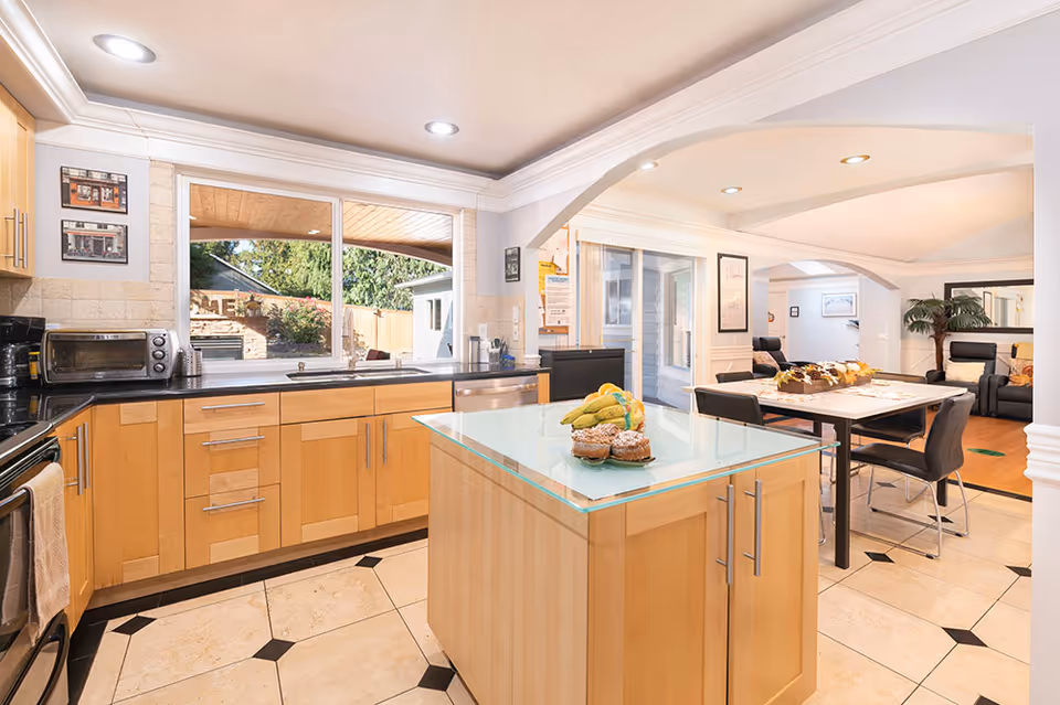 Bright kitchen and dining area in a senior living facility featuring a central island.