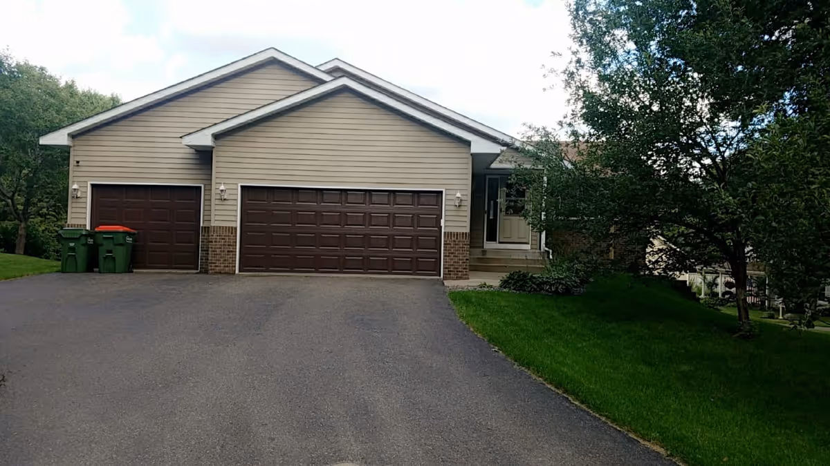Front exterior of a residential building with a three-car garage and driveway.