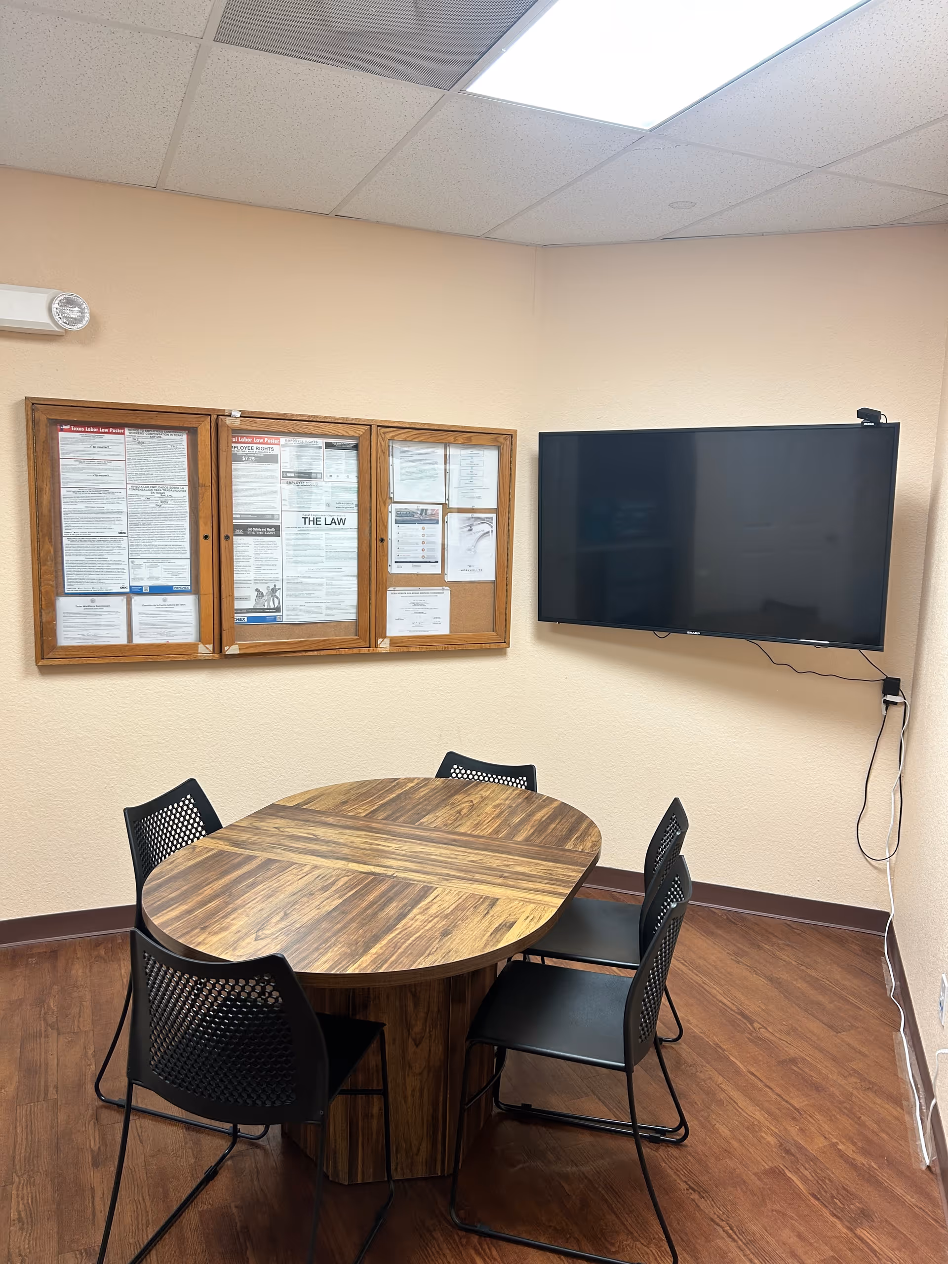 Small conference room in a senior living facility with round table, chairs, bulletin board, and TV.