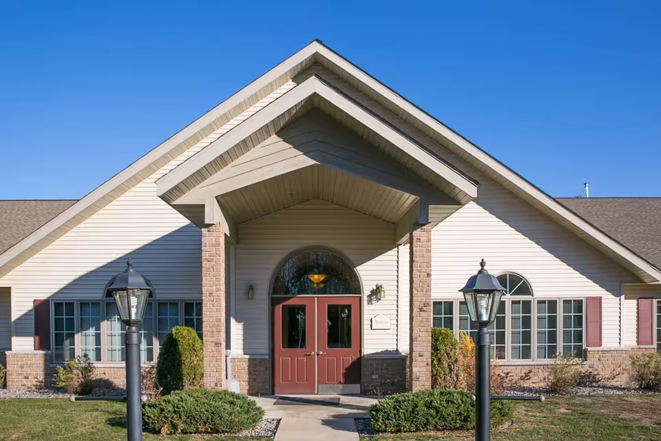 Front entrance of Zion's II Assisted Living with maroon doors and landscaping.