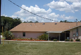 Front exterior of a single-story pink building with landscaped lawn under a blue sky.