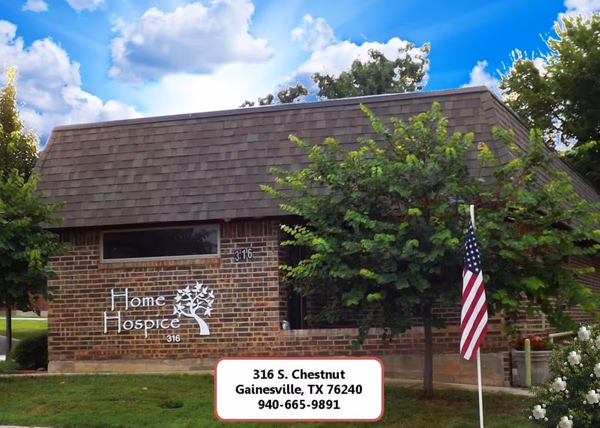 Brick hospice building with trees, an American flag, and a front sign.