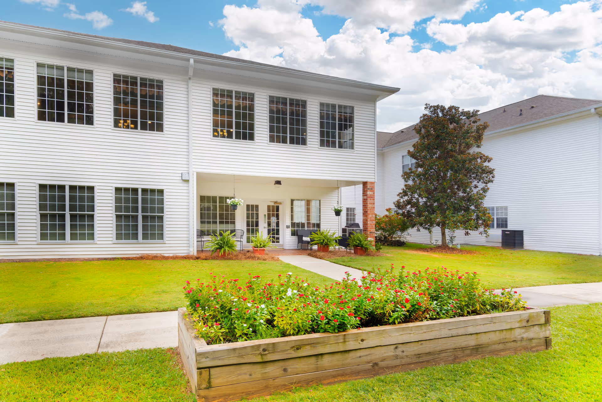White two-story Brookdale Carrollton building with large windows, front entrance, and flower bed.