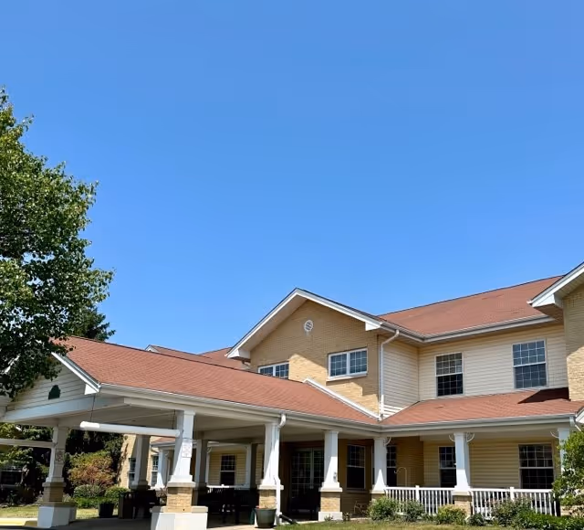 Exterior view of Allure of Zion senior living facility with covered entrance and blue sky.