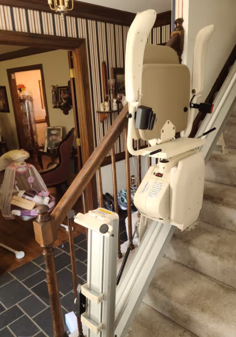 A stairlift chair installed on a staircase inside a home interior.