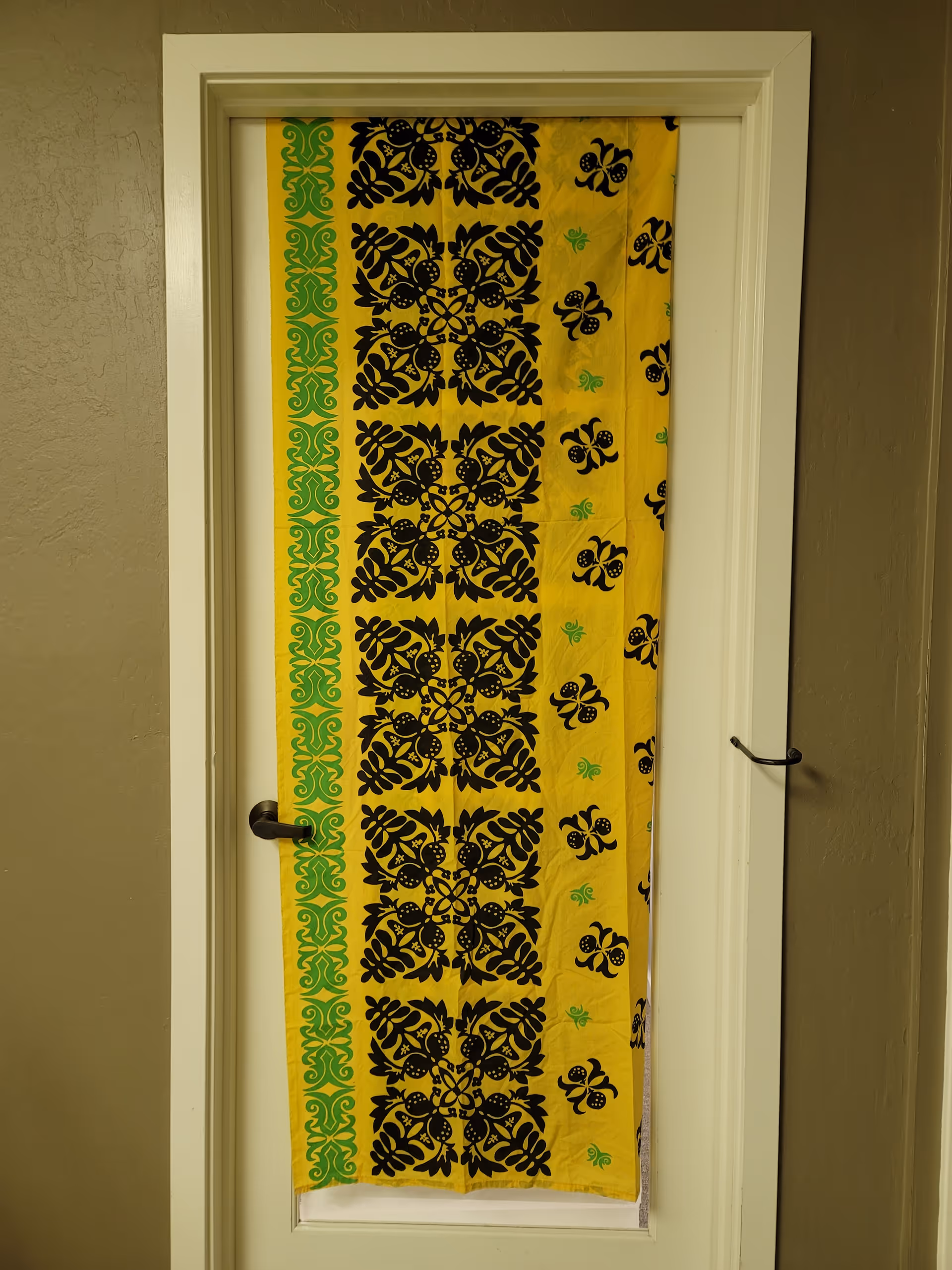 Interior doorway with a yellow, black, and green patterned curtain hanging inside.