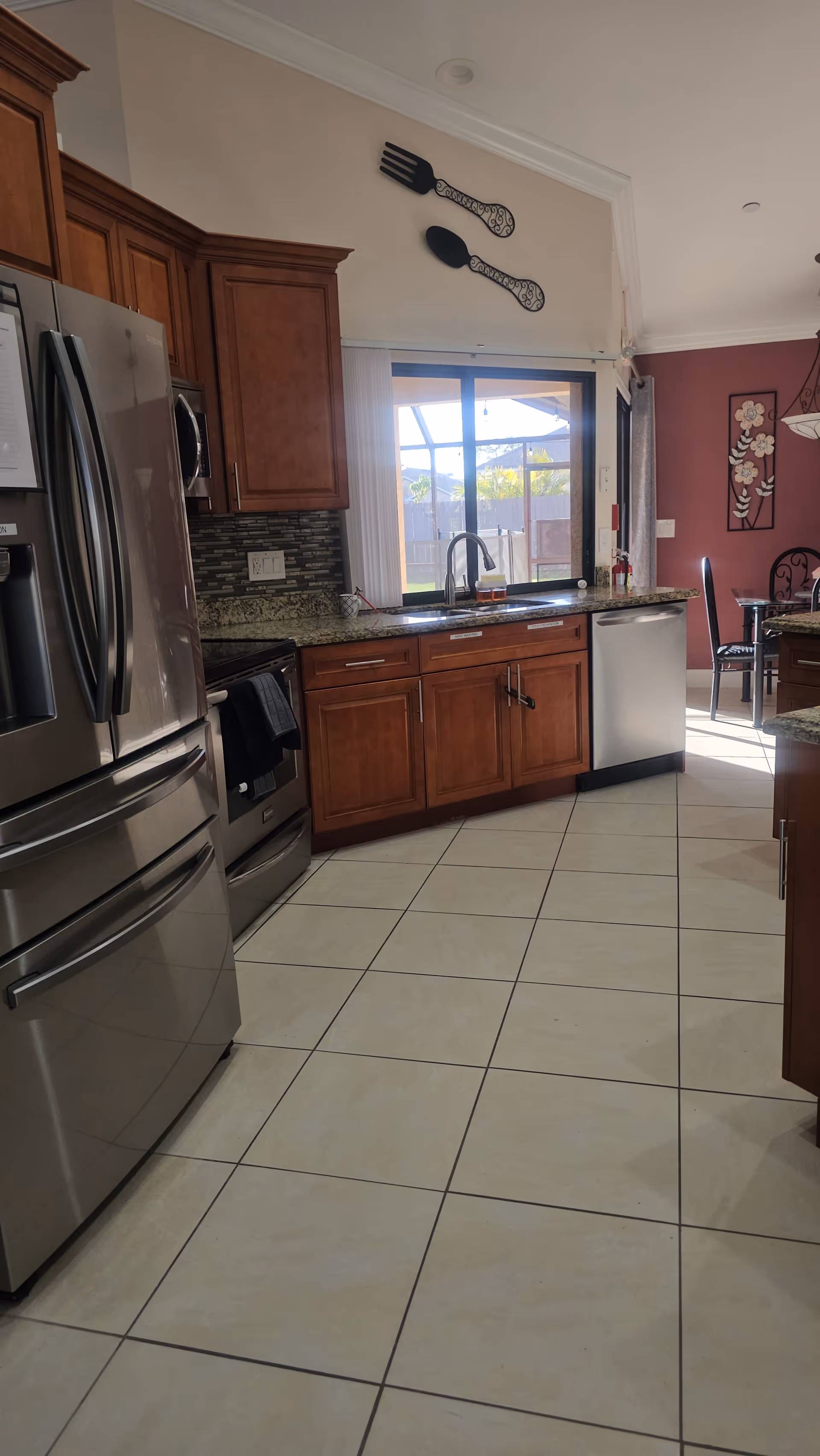 Modern kitchen with stainless appliances, wooden cabinets, and a view of the outdoors.