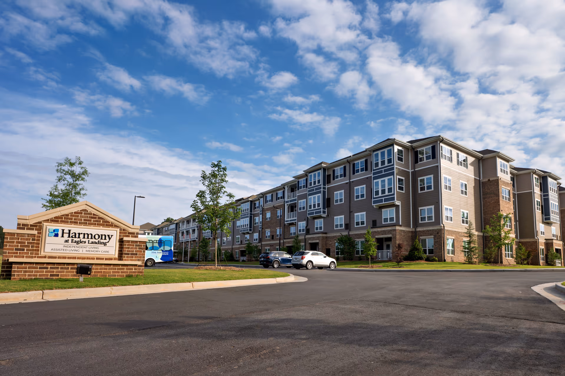 Exterior view of Harmony at Eagles Landing senior living community with sign and parking.