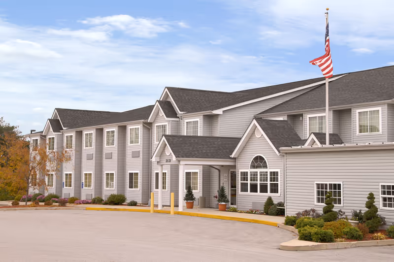 Exterior view of a gray senior living center with an American flag at the entrance.