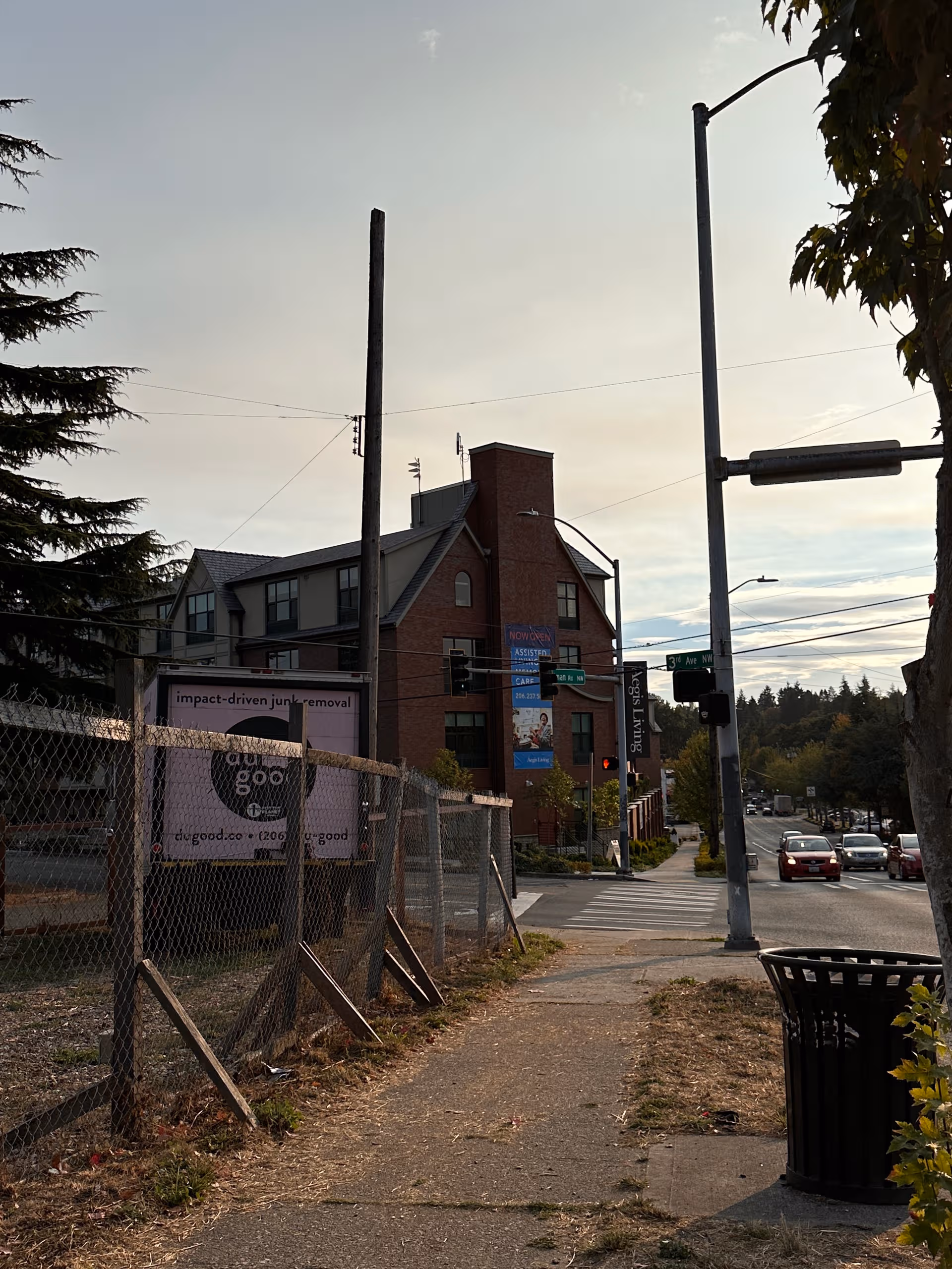 Street view of a brick building with a chain-link fence and sidewalk.