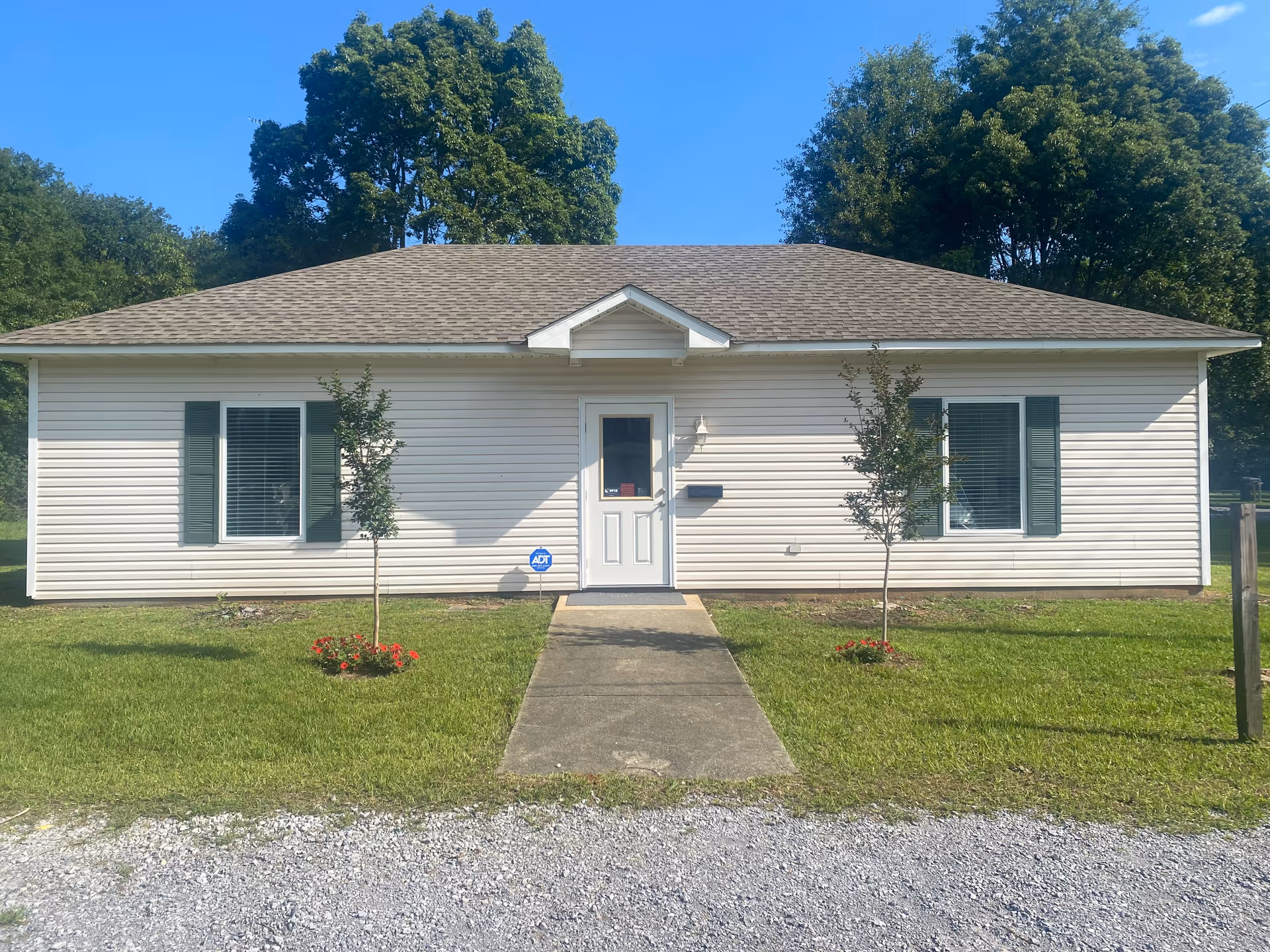 Single-story facility exterior with front entrance, small lawn, and trees.