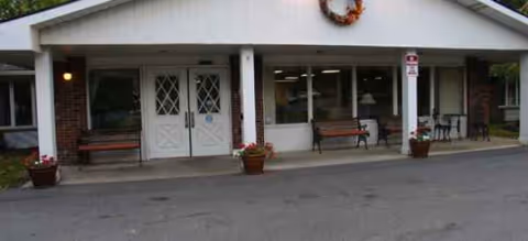 Front entrance of Brookdale East Side senior living with benches and potted plants.