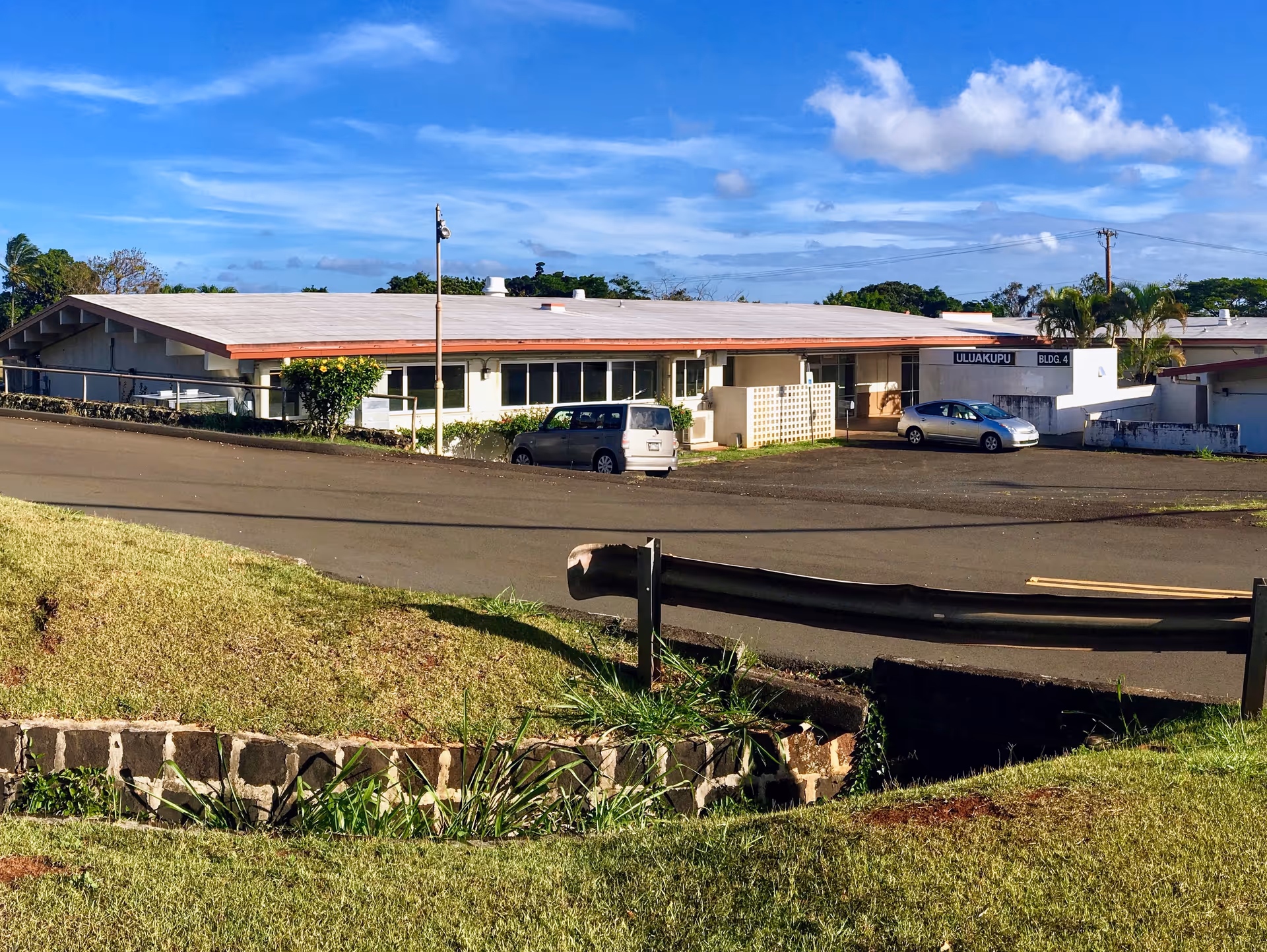 Single-story exterior of a Hawaii health department facility with parking and blue sky.