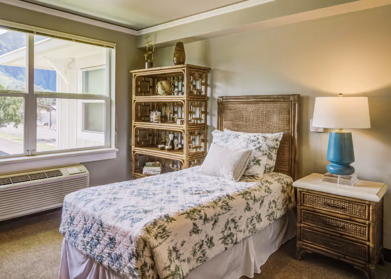 Cozy bedroom with bed, wicker headboard, and matching nightstand.