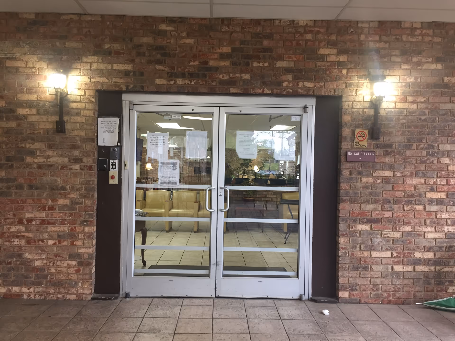 Brick exterior entrance with glass double doors and indoor seating visible inside.