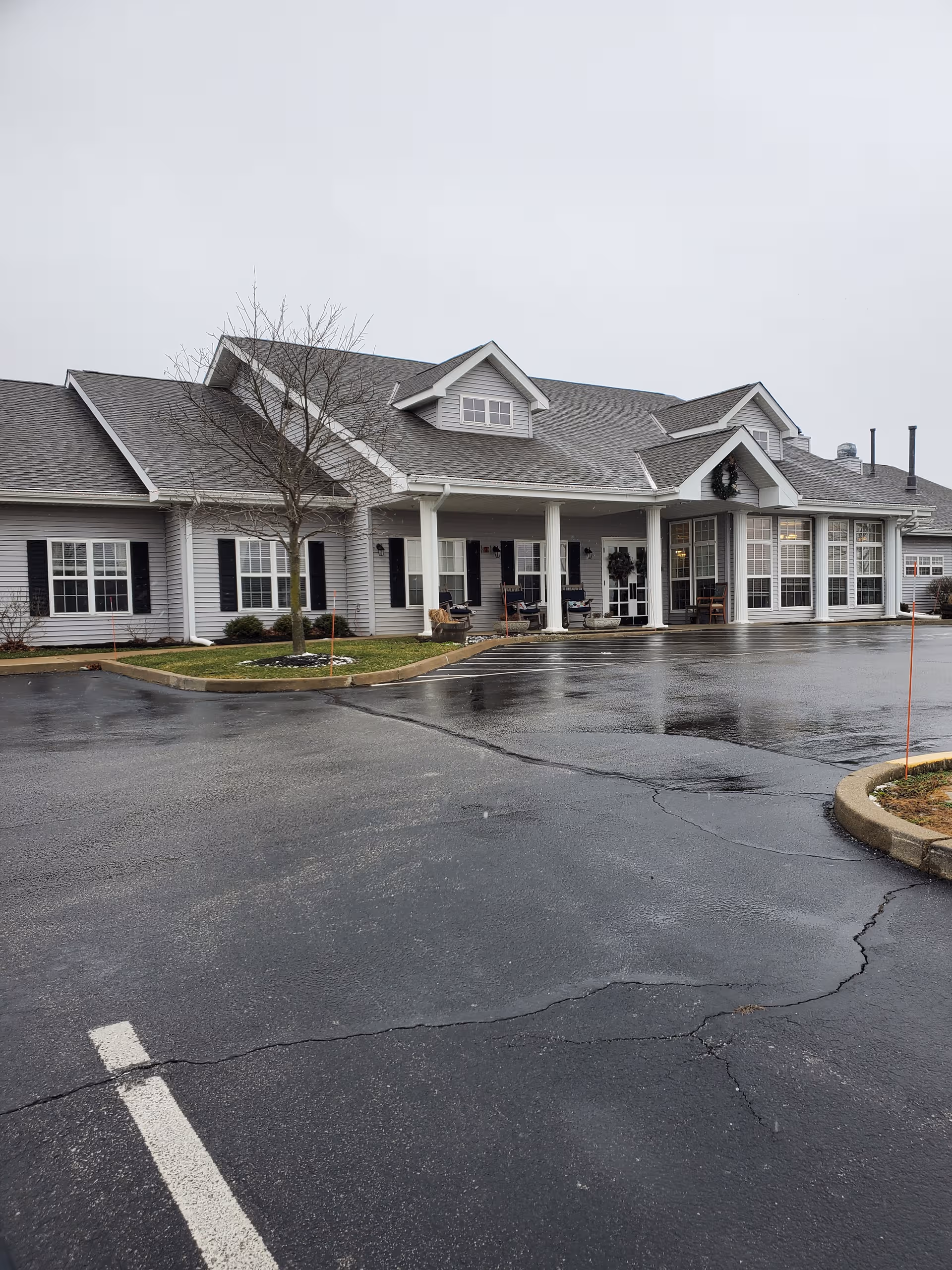 Front exterior of Digby Place senior living facility with a wet parking lot.