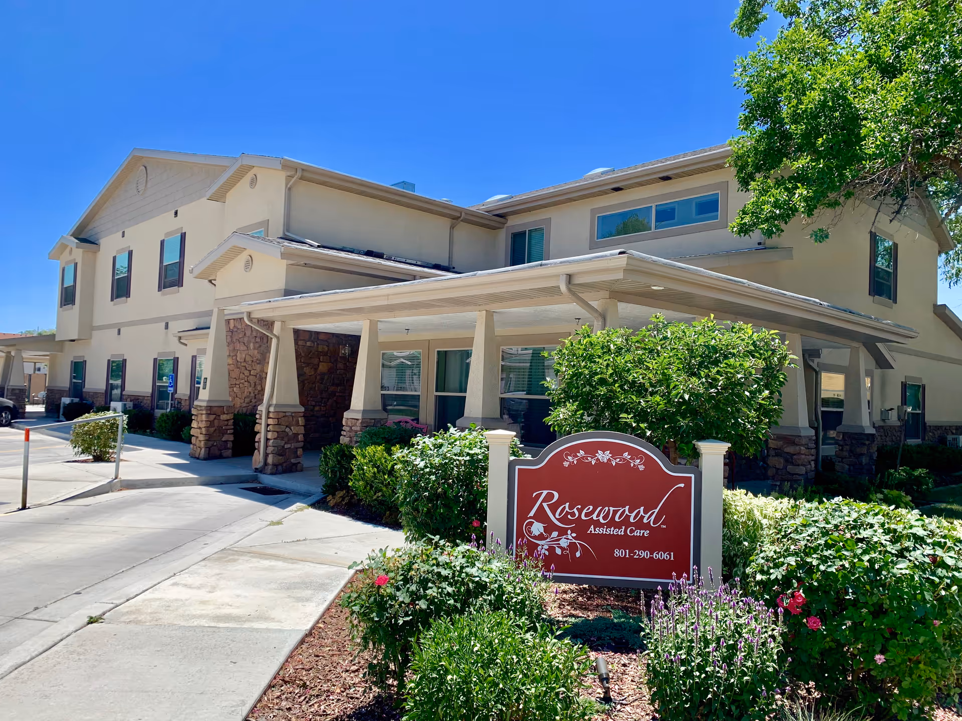 Front exterior of Rosewood Assisted Care with sign, walkway, and landscaped entrance.