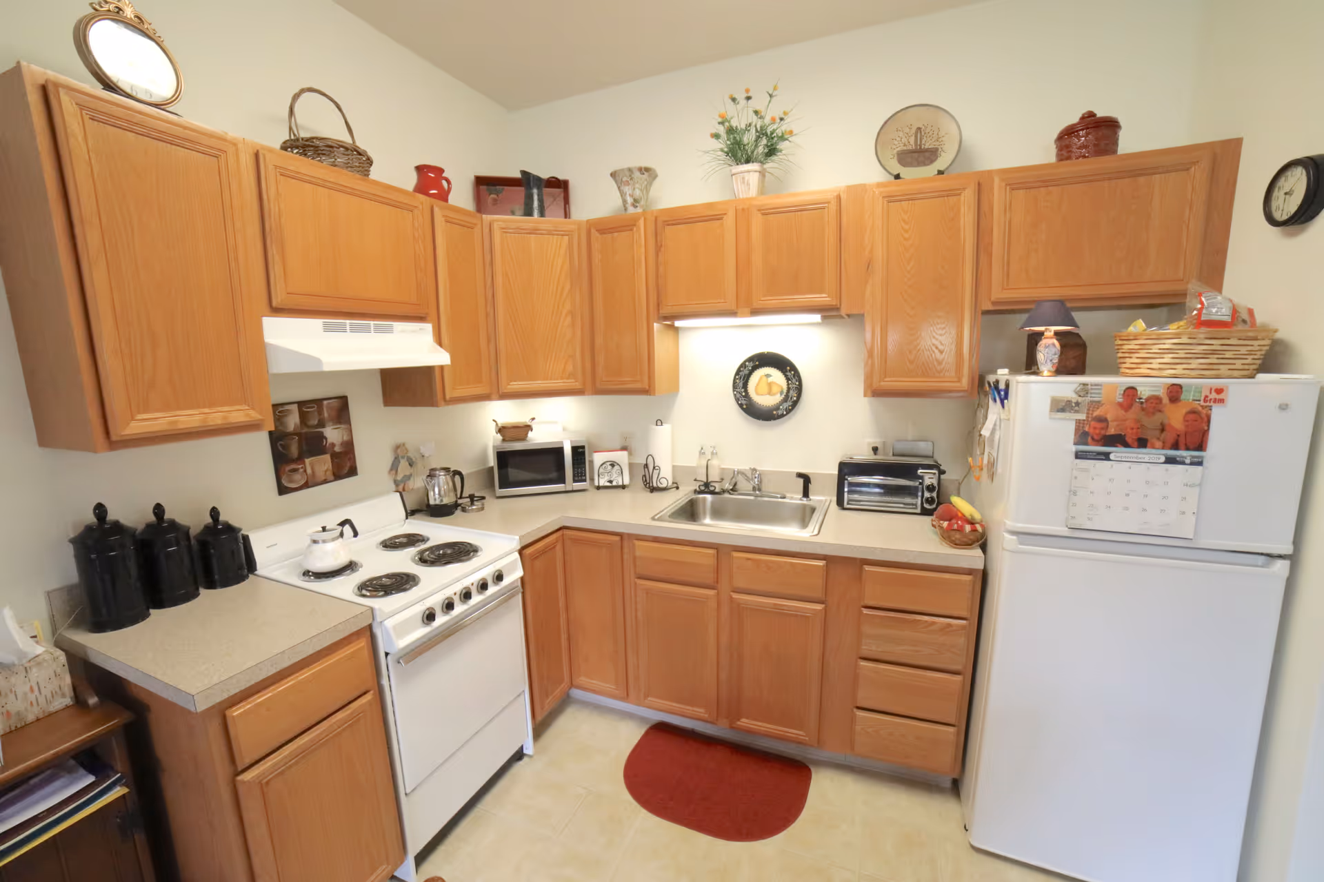 U-shaped kitchen with wooden cabinets, white stove, sink, and refrigerator in a cozy space.