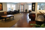 Lobby-style indoor common area in a senior living facility with sofas and tables.