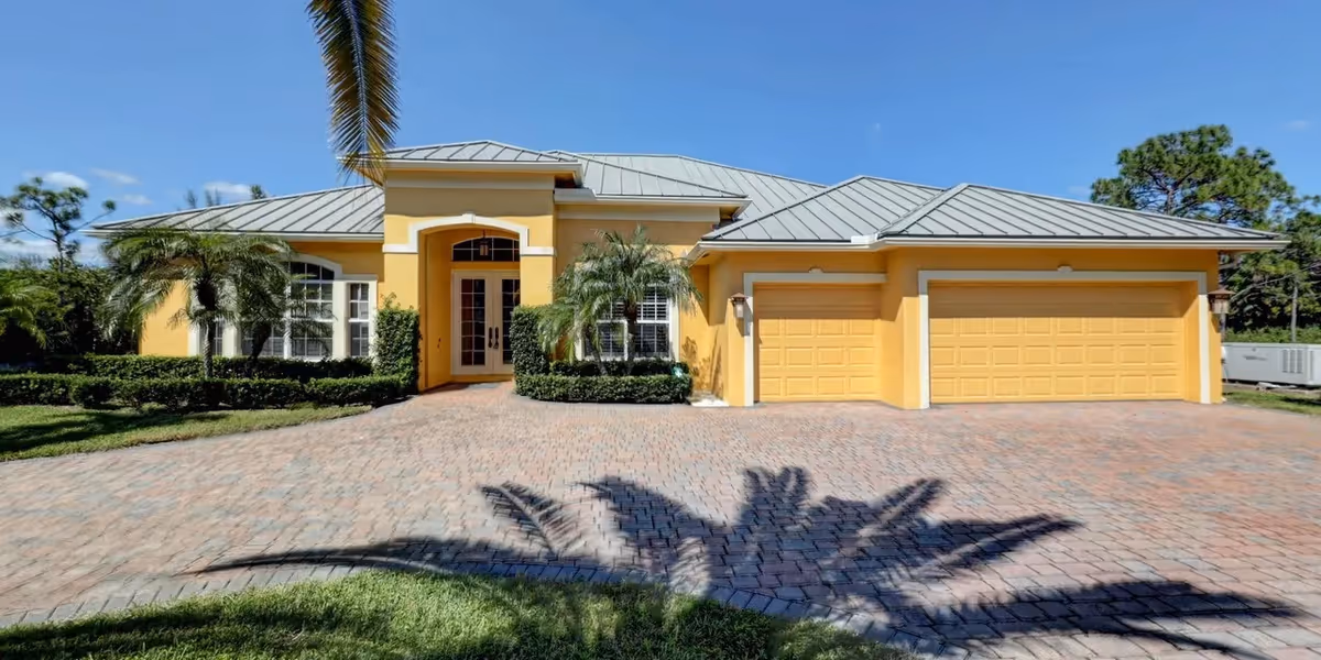 Yellow assisted living facility with a three-car garage and palm trees in front.