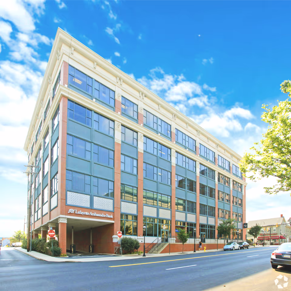 Exterior view of a modern brick-and-glass building along a sunny city street.