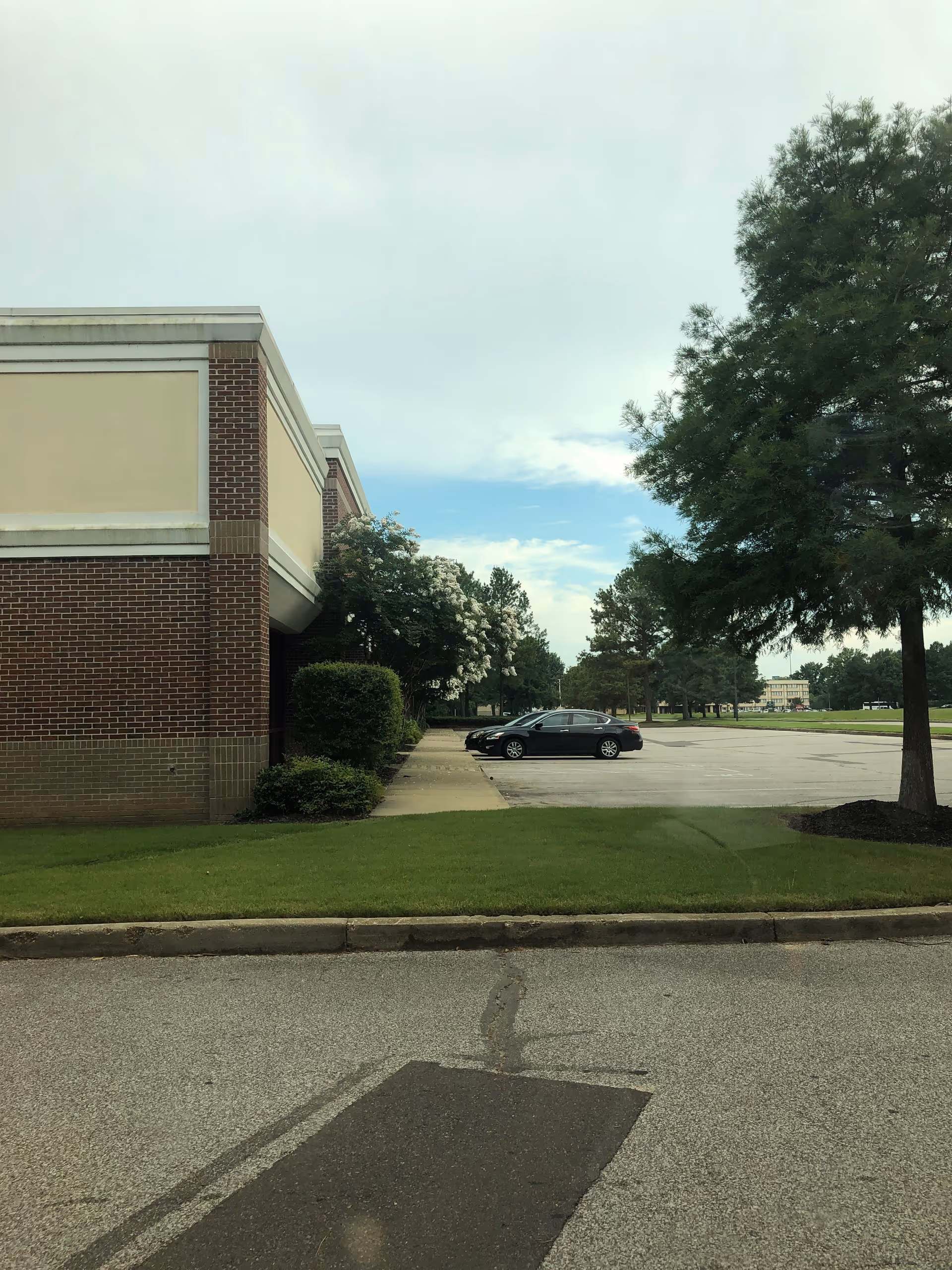 Exterior view of a brick facility with a parking lot and trees.