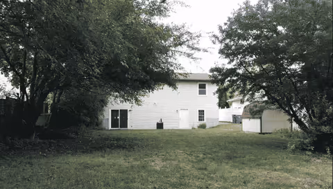 Rear exterior of a white Life Choice Adult Home building with trees and a grassy yard.